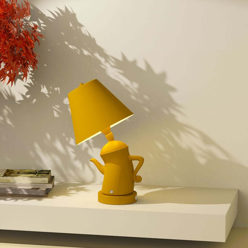 Alice Dream Kettle Lamp placed on a shelf, showcasing its whimsical kettle design and touch dimming feature.