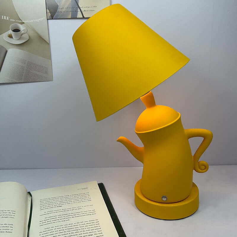Alice Dream Kettle Lamp – Touch Dimming Wireless Charging Table Light in vibrant yellow, beside an open book.
