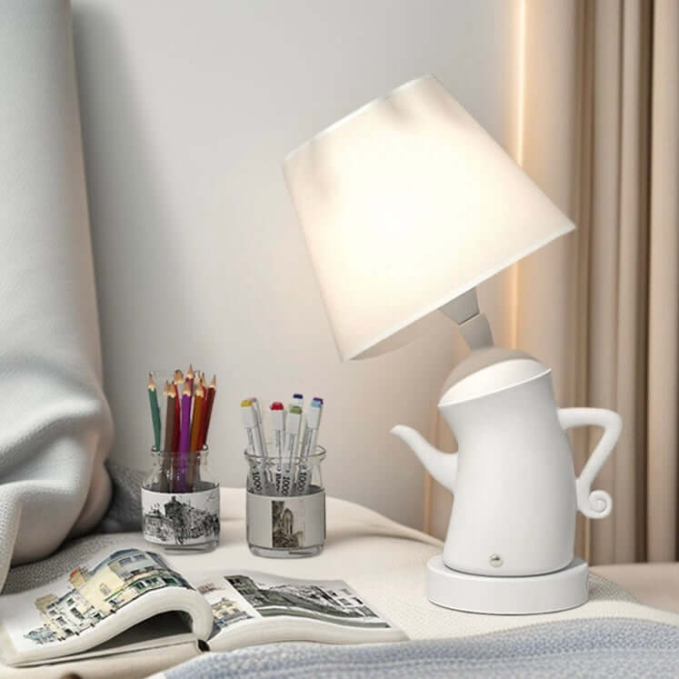Alice Dream Kettle Lamp on bedside table with ambient light and colorful pens in a jar.