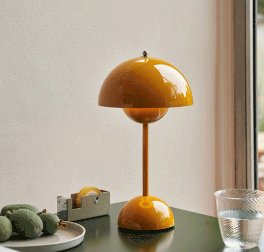 How to choose a desk lamp: bright yellow desk lamp beside a glass of water and decorative items on a table.