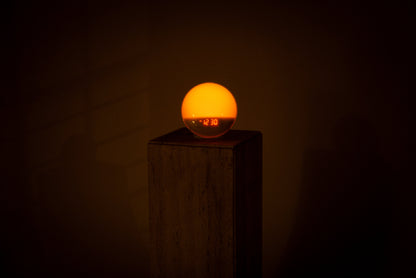 Lumiosa dawn simulator gently waking you with soft light, displayed on a neutral pedestal in a dimly lit room.
