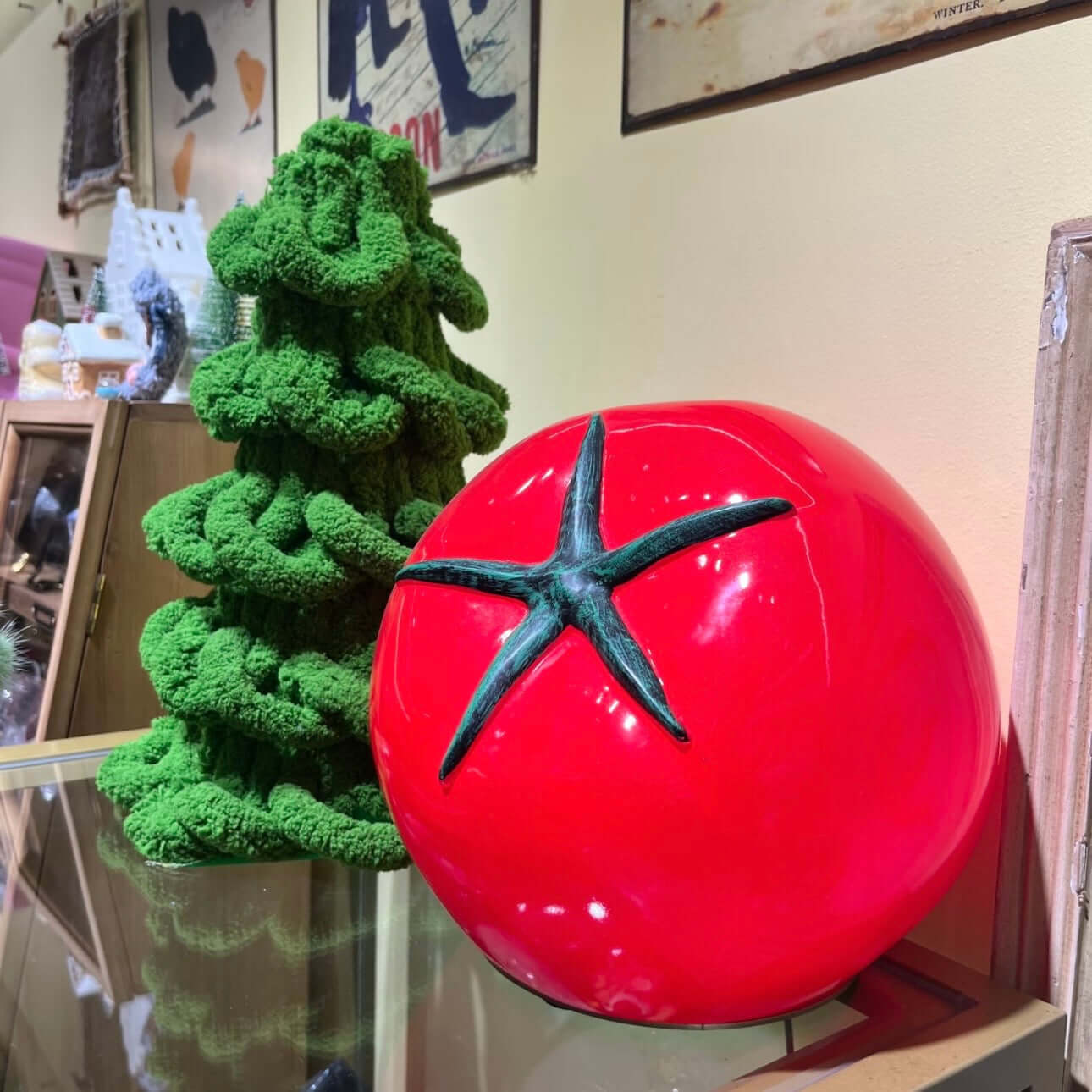 Tomato night light displayed beside a green decorative tree, showcasing its quirky design and vibrant color.