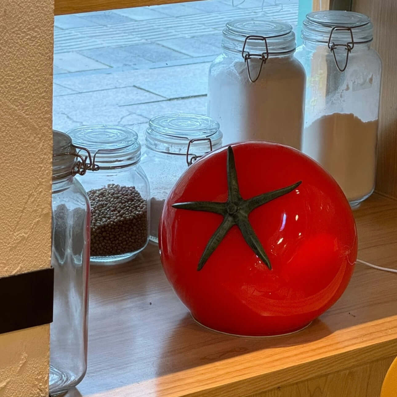 Tomato night light on a wooden shelf next to glass jars, perfect for bedside decor or accents in a cozy space.