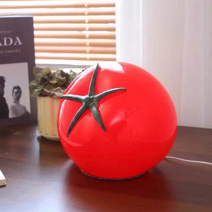 Tomato night light on a wooden table with decorative items in the background, showcasing its unique design and soft glow.