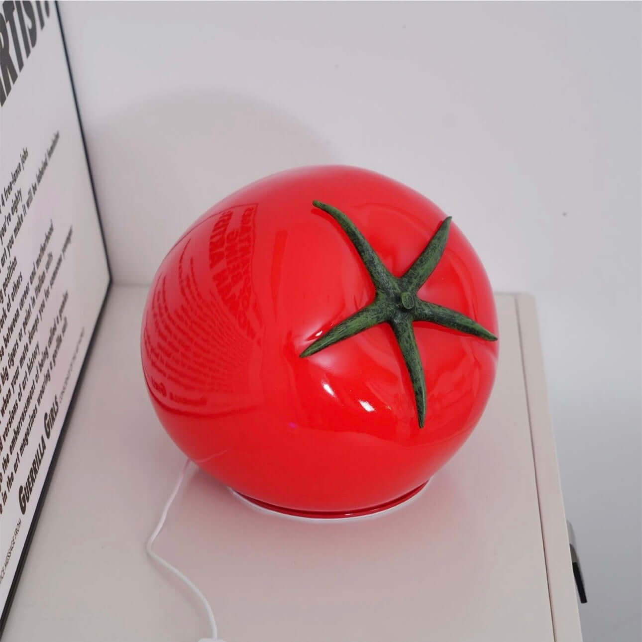 Tomato night light on bedside table illuminating the space with its quirky design and soft LED glow.