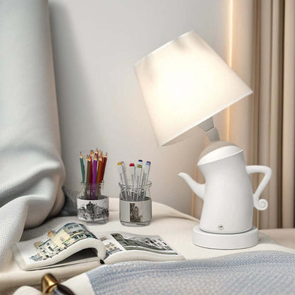 Alice Dream Kettle Lamp illuminating a bedside table with art supplies and a book.