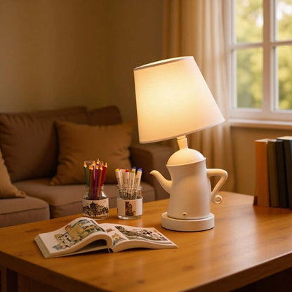 Alice Dream Kettle Lamp on a wooden table with a cozy living room background featuring books and stationery.