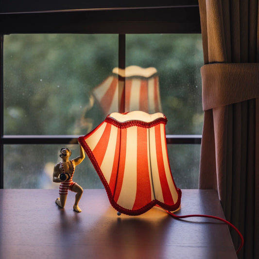 Circus Strongman Table Lamp with red and white striped shade on a bedside table, showcasing vintage charm.