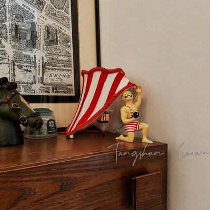 Circus Strongman Table Lamp on a wooden dresser, showcasing vintage charm and playful design.