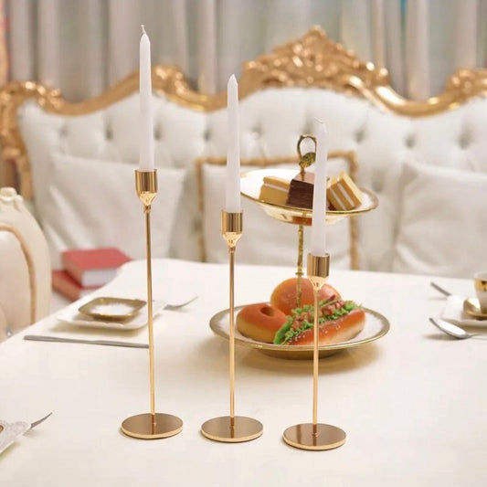 Elegant gold candlestick holders with white candles, enhancing a sophisticated dining table setting.