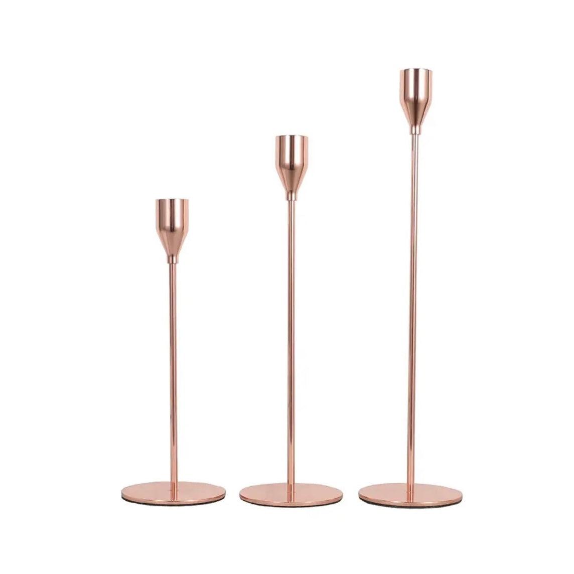 Set of three elegant rose gold candlestick holders, perfect for enhancing home decor and illuminating spaces.