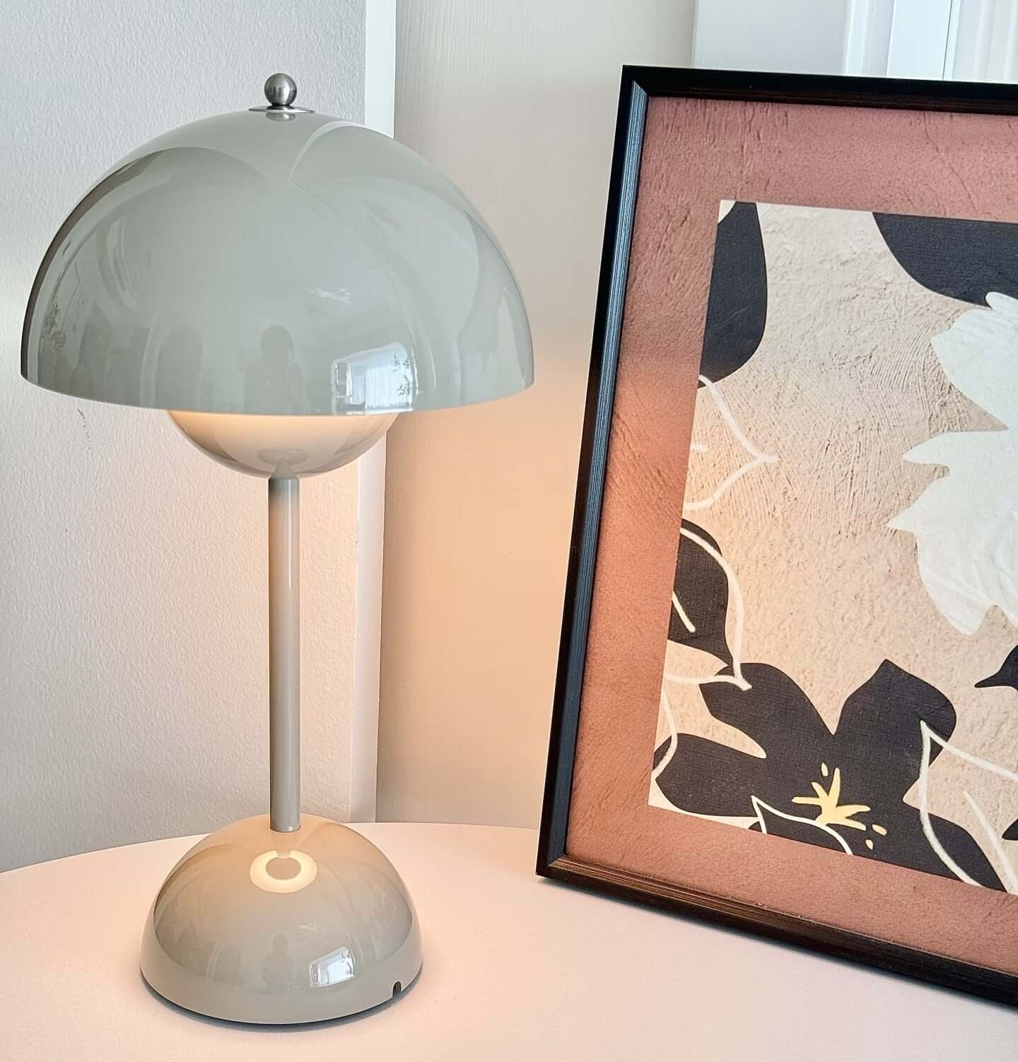 Touch LED table lamp with a gray dome shade beside a framed floral art print on a table.