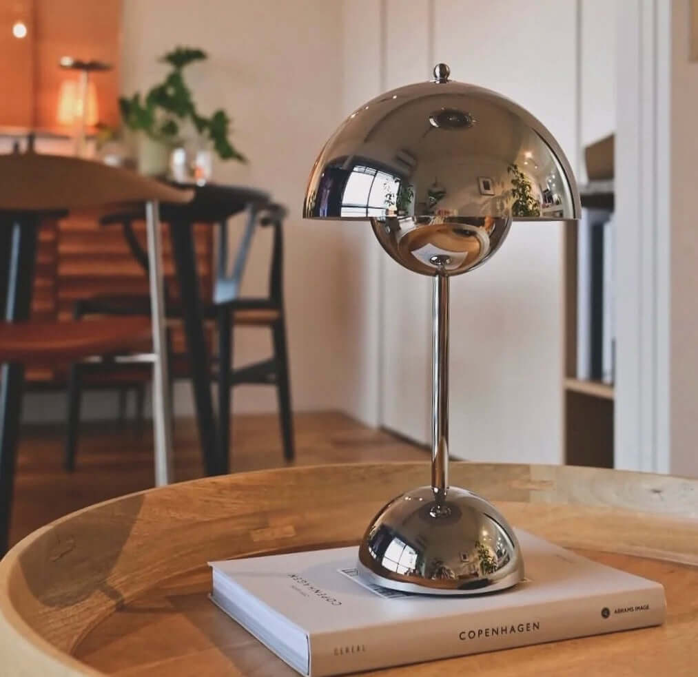 Stylish chrome touch LED table lamp on a coffee table with books in a modern home interior.