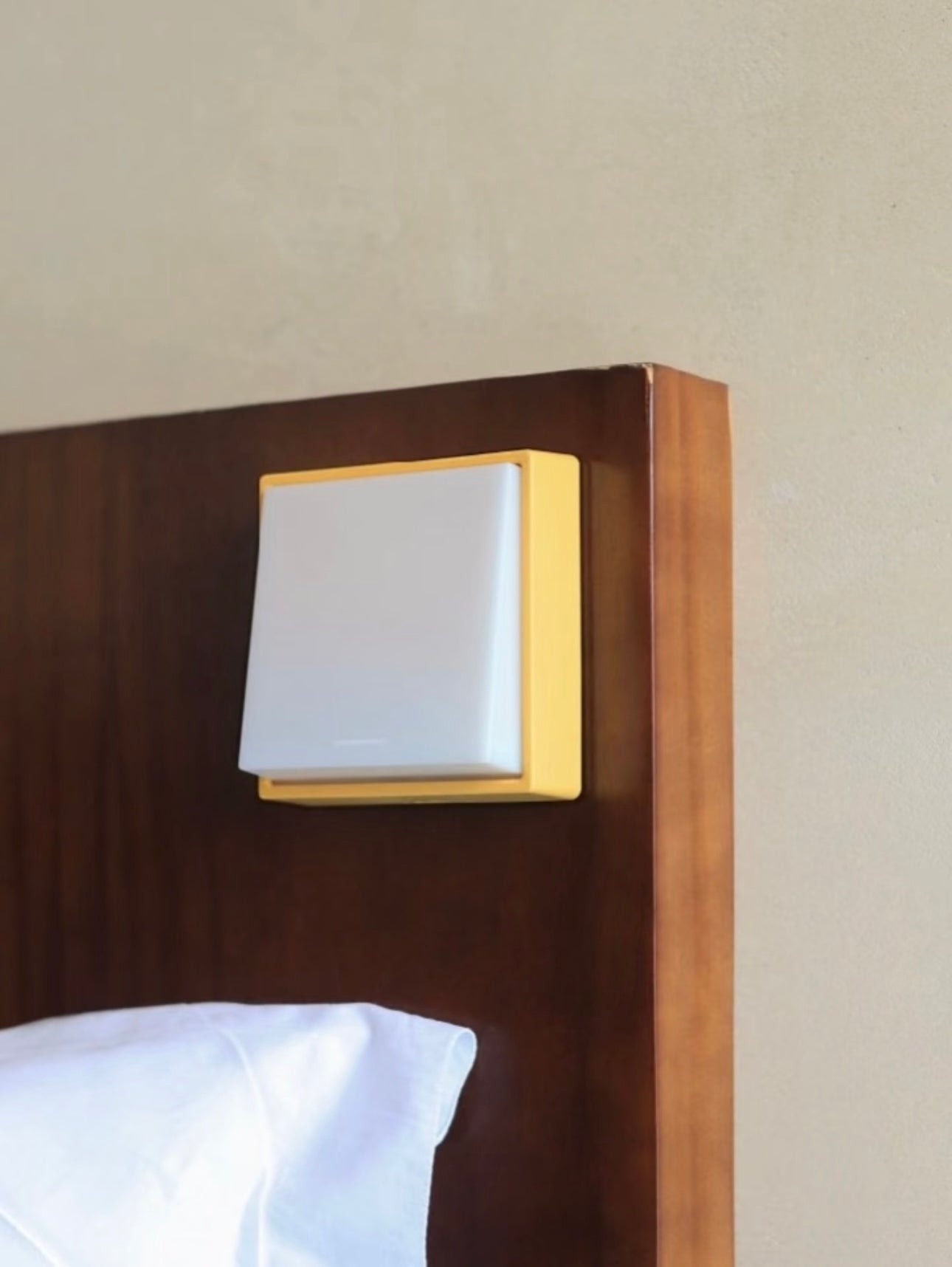 Switch-shaped nightlight mounted on wooden bed headboard, featuring a sleek design and adjustable brightness.