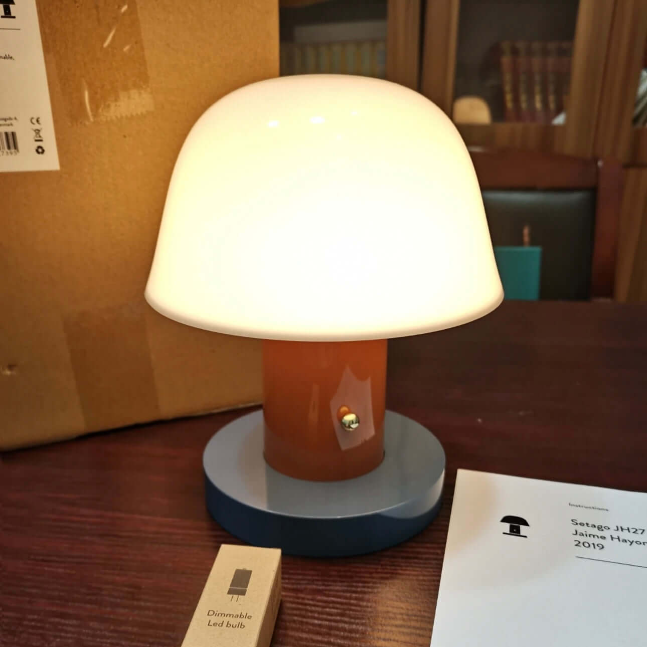 Seta mushroom charging desk lamp with a stylish dome shade and dimmer, placed on a wooden desk.