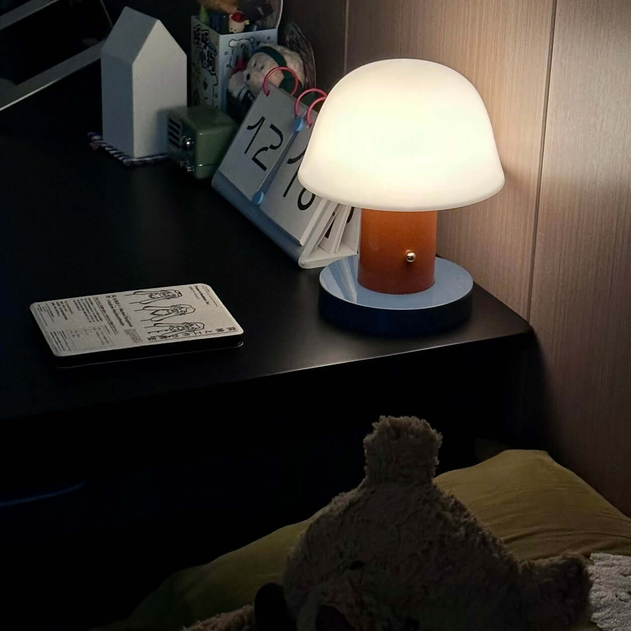 Seta mushroom charging desk lamp illuminated on a desk, showcasing its stylish design and wire-free convenience.