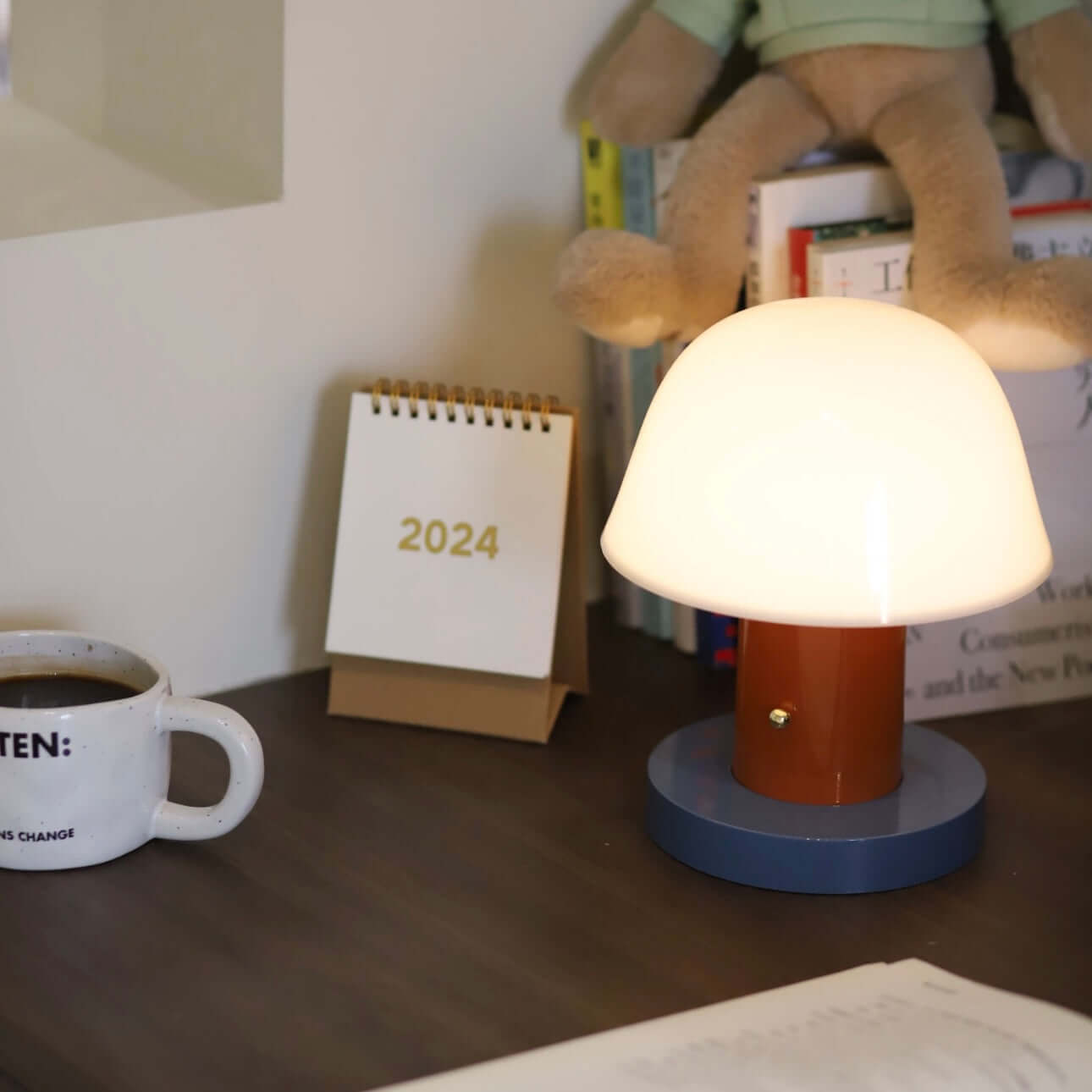 Seta mushroom charging desk lamp on a workspace with a coffee cup and 2024 calendar, showcasing wire-free design and stylish functionality.