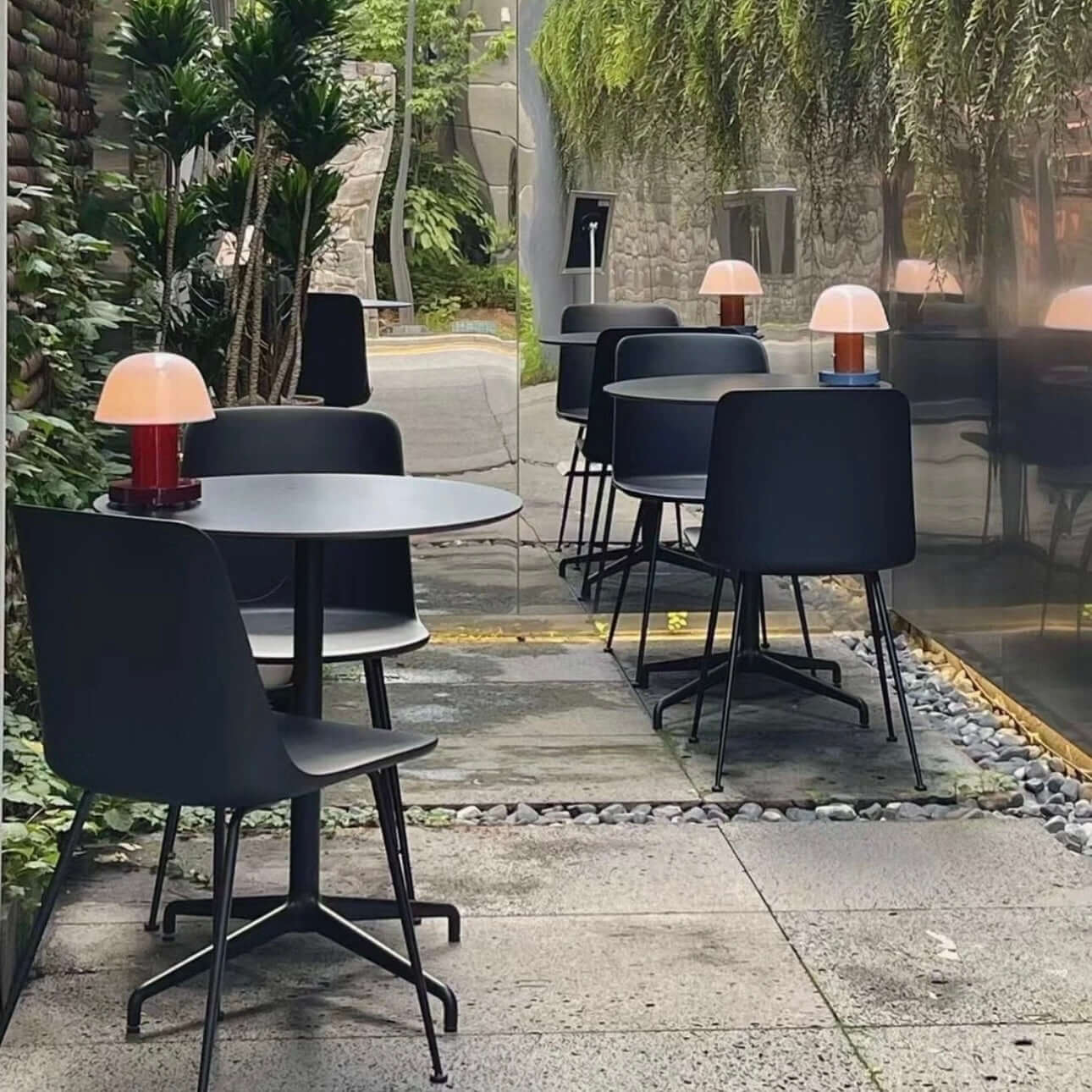 Outdoor seating area featuring modern tables and lamps in a lush garden setting.