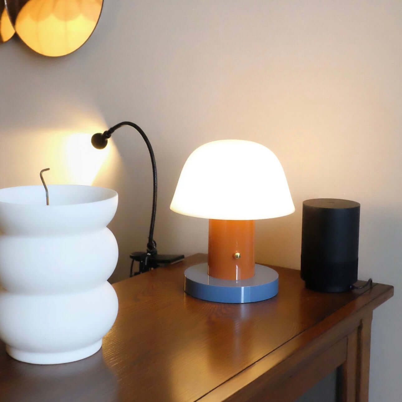 Stylish Seta mushroom charging desk lamp on a wooden table with other decorative items.