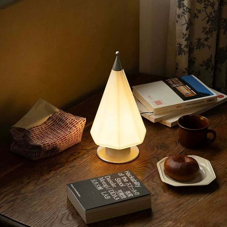 Handcrafted cedar lamp on a wooden table, casting a warm glow, beside books and a cozy breakfast.