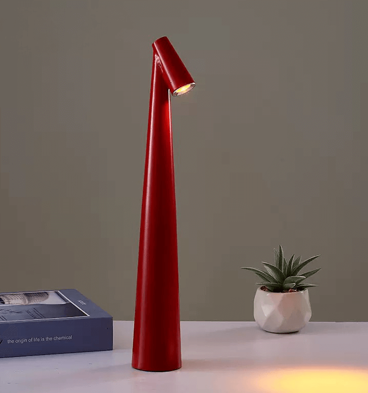 Modern red LED desk lamp with a sleek design, illuminating a workspace beside a small potted plant.