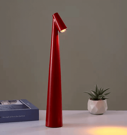 Modern red LED desk lamp with a sleek design, illuminating a workspace beside a small potted plant.