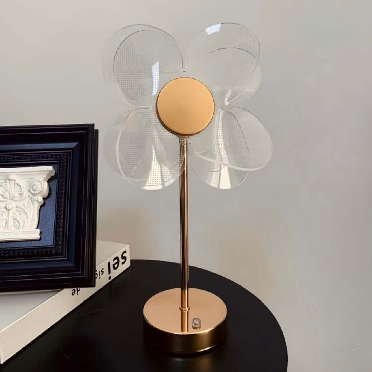 Nordic Clover table lamp with a clover-shaped design, gold stand, and transparent shade on a black table.
