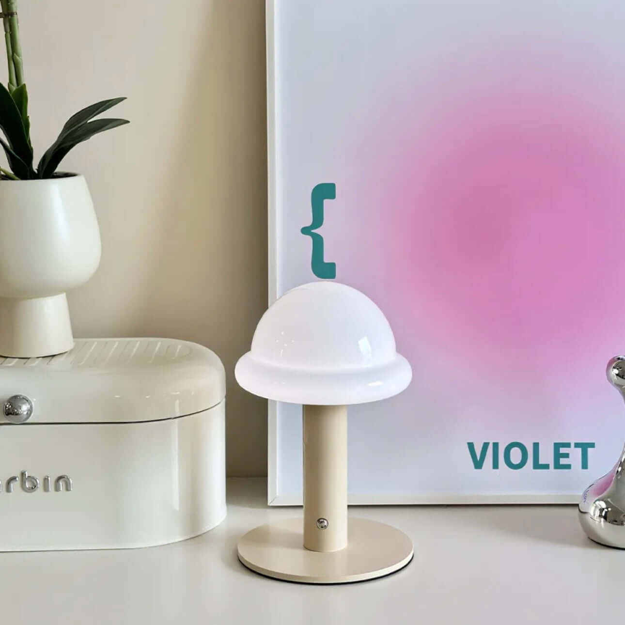 Candy table lamp with white dome shade, beige base, and colorful backdrop, perfect for mood lighting.