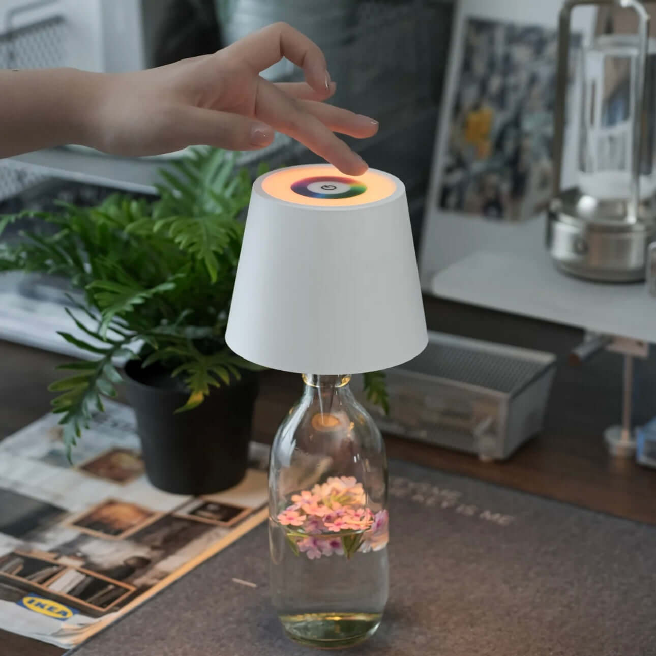 Hand adjusting a touch lamp on a creative wine bottle lamp with flowers, showcasing its unique design and LED features.