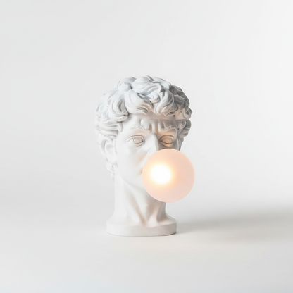 White matte resin David sculpture table lamp blowing glowing frosted glass bubble on white background