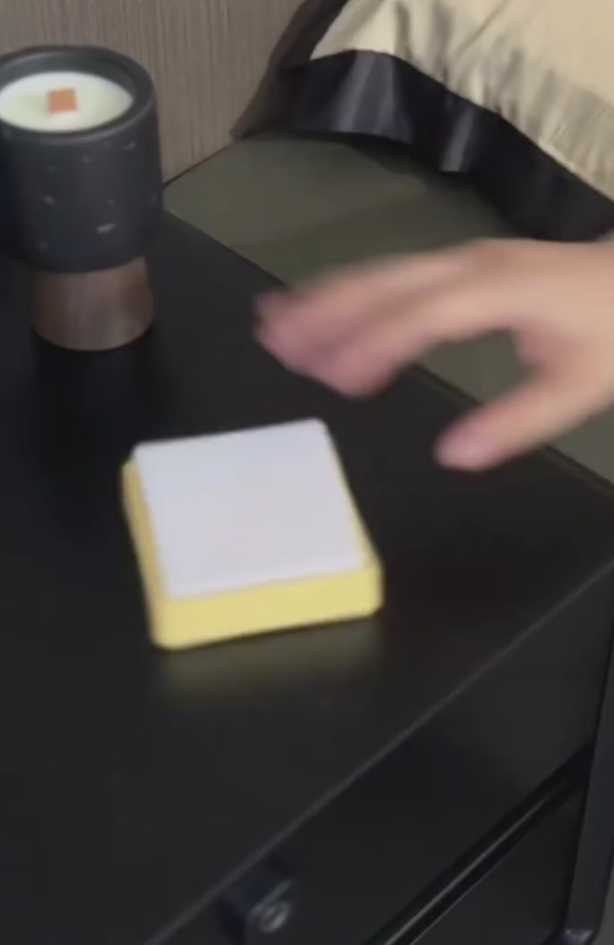 Person tapping a switch-shaped nightlight on a bedside table for adjustable lighting.